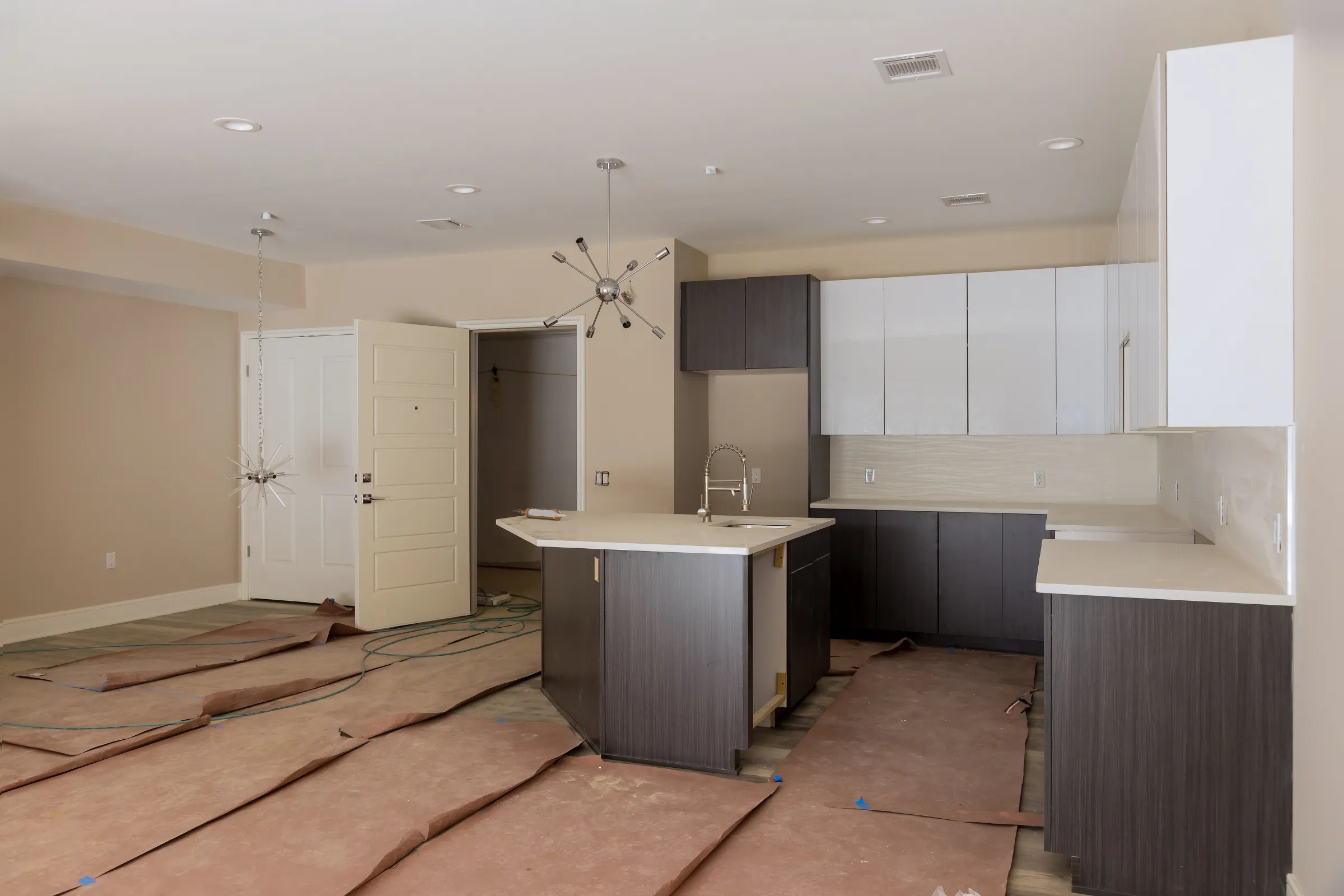 Kitchen remodeling in Los Angeles with modern cabinets, kitchen island, countertop installation, protected floors, and renovation work in progress