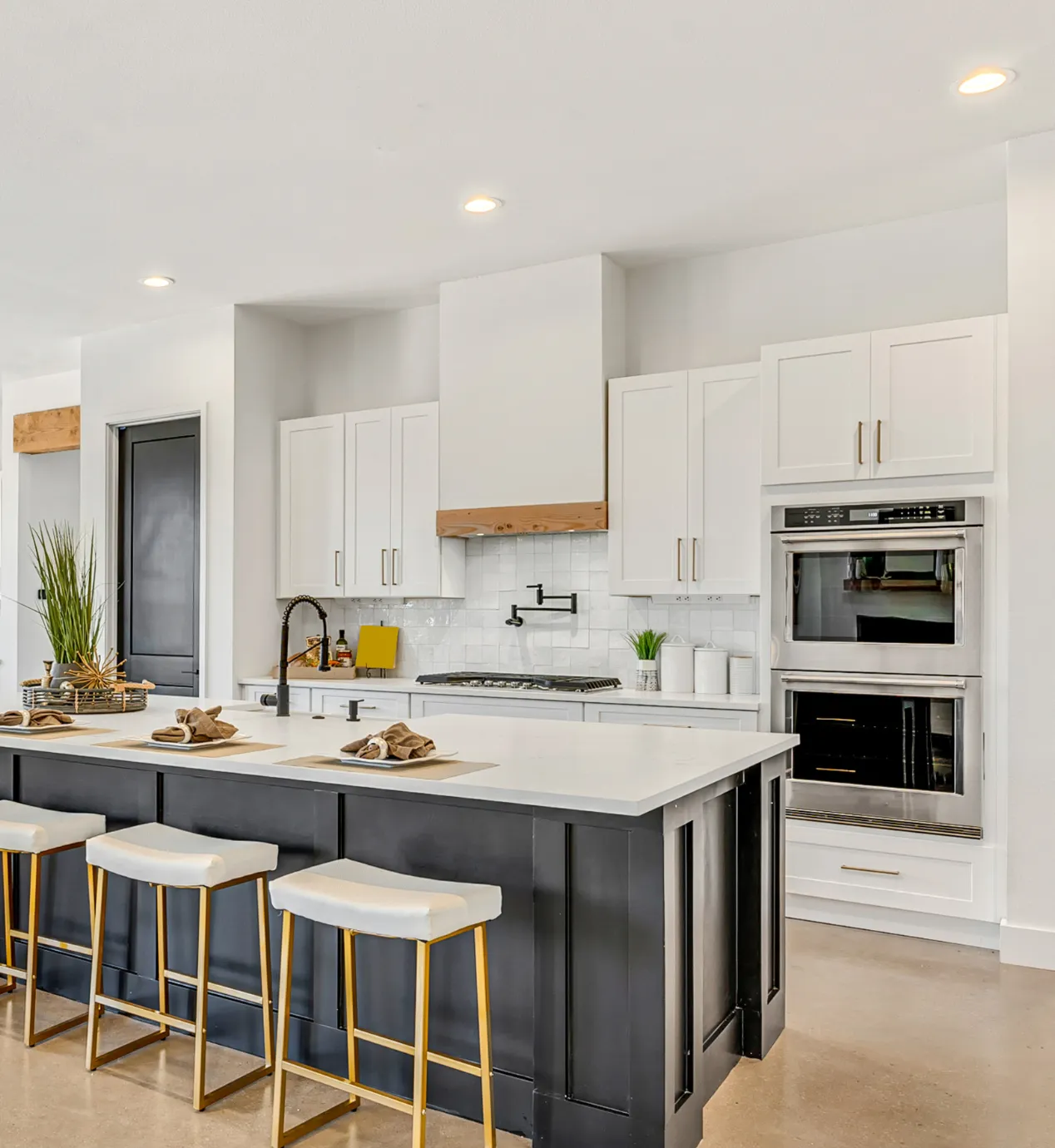 Finished kitchen remodeling project in Los Angeles with white cabinets, black island, quartz countertops, built-in appliances, and modern open layout