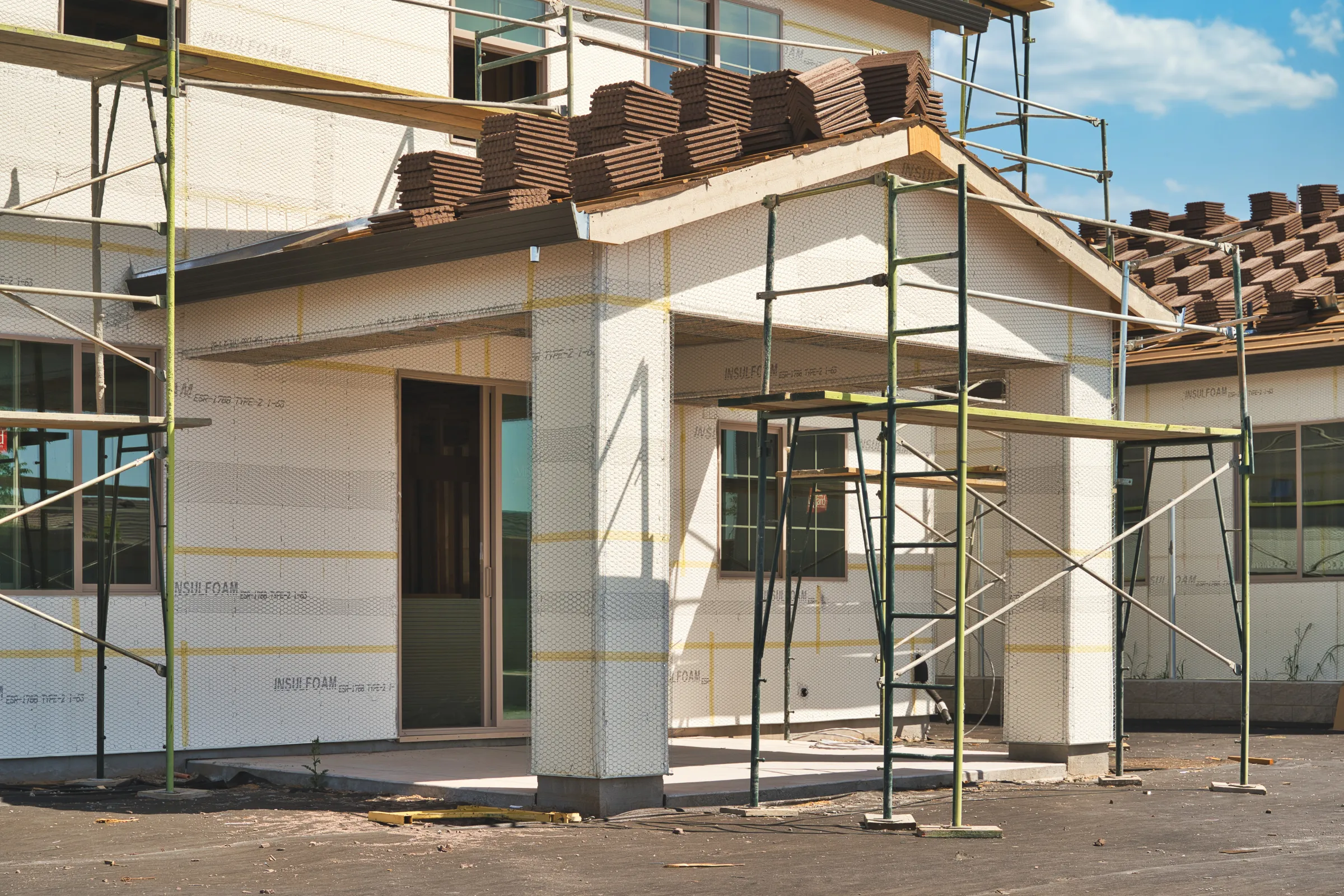 New home construction in Los Angeles with custom home exterior, scaffolding, roofing work, and residential build in progress